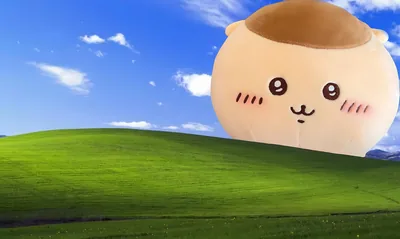 Giant Kurimanju plush rising behind green hills under blue sky for PC Wallpaper